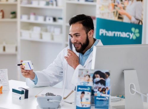 Independent pharmacist reviewing prescription reimbursement and PBM fee adjustments in a retail pharmacy setting
